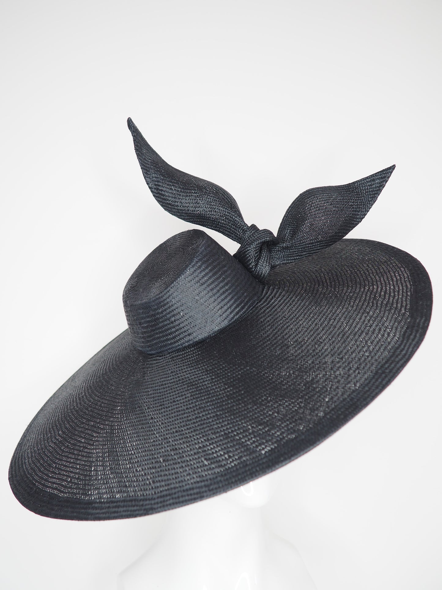 Derby Pose-  Slanted brim parisissal straw with asymmetric crown and wires knot detail