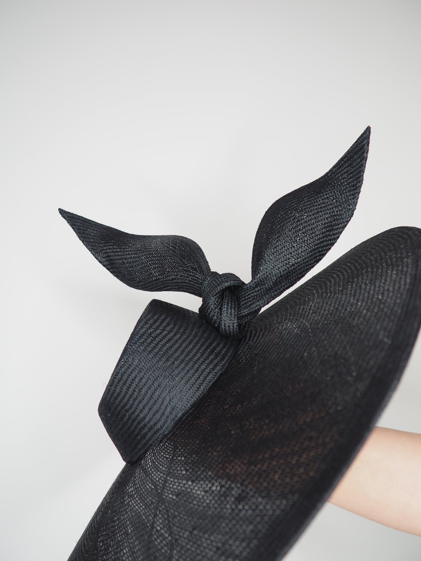 Derby Pose-  Slanted brim parisissal straw with asymmetric crown and wires knot detail